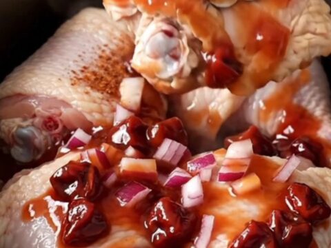 Slow cooker cherry chipotle chicken thighs with a rich dark red glaze served on a white plate.