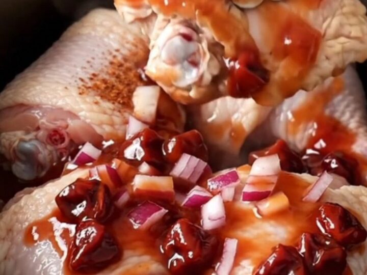 Slow cooker cherry chipotle chicken thighs with a rich dark red glaze served on a white plate.