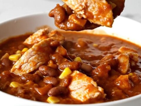 A top-down view of chicken enchilada chili in a black slow cooker insert.