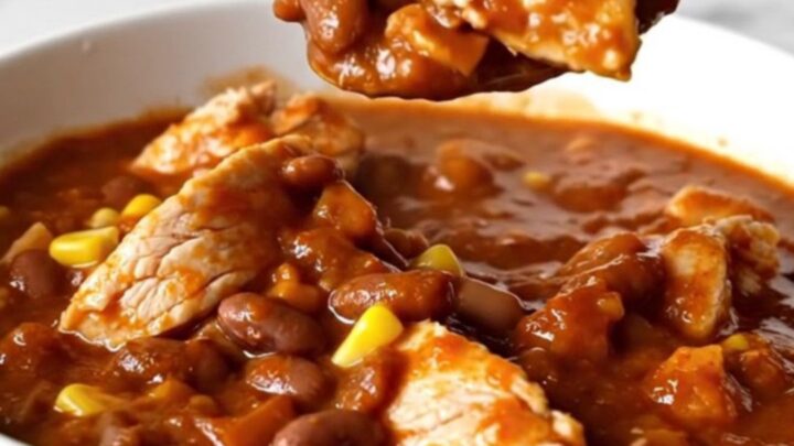 A top-down view of chicken enchilada chili in a black slow cooker insert.