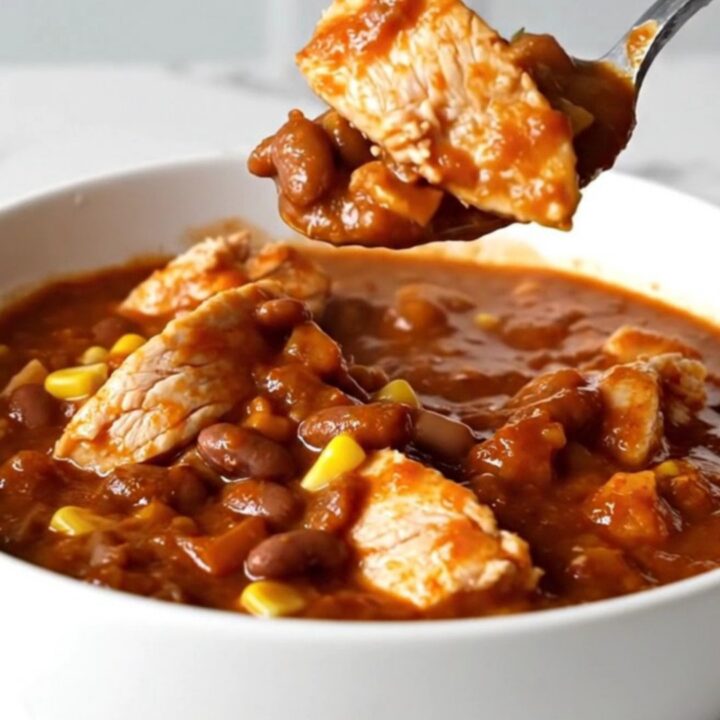 A top-down view of chicken enchilada chili in a black slow cooker insert.