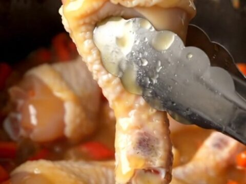 A close-up of honey habanero chicken drumettes in a slow cooker, glazed in a thick, amber, spicy honey sauce.