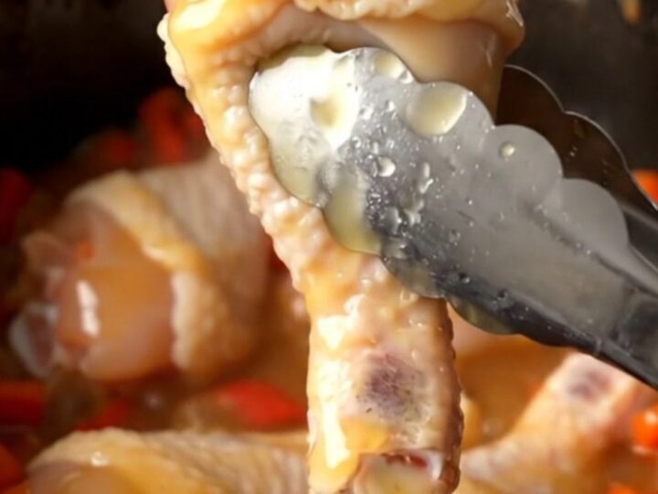 A close-up of honey habanero chicken drumettes in a slow cooker, glazed in a thick, amber, spicy honey sauce.