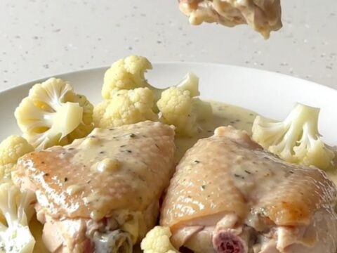 Creamy chicken Alfredo thighs with cauliflower in a black slow cooker insert.