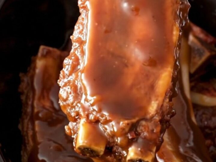 A close-up of tender, molasses-glazed country-style ribs served in a rustic dish with soft onions.