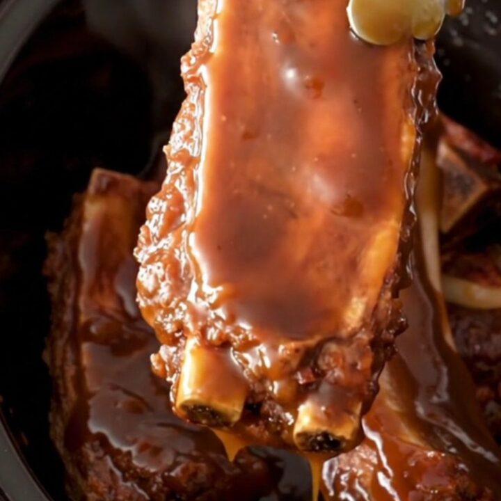 A close-up of tender, molasses-glazed country-style ribs served in a rustic dish with soft onions.
