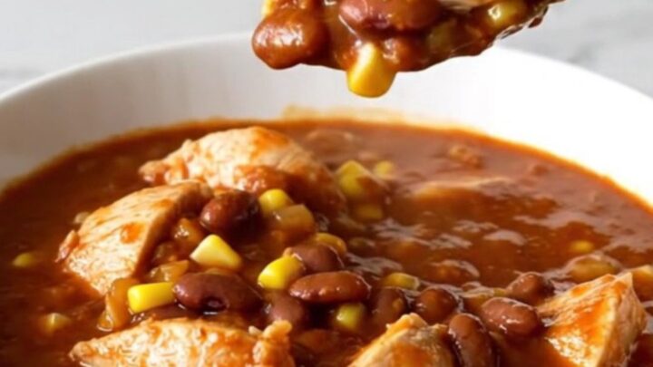A shallow bowl filled with Crockpot Chicken Tamale Chili featuring chunks of white chicken, yellow corn