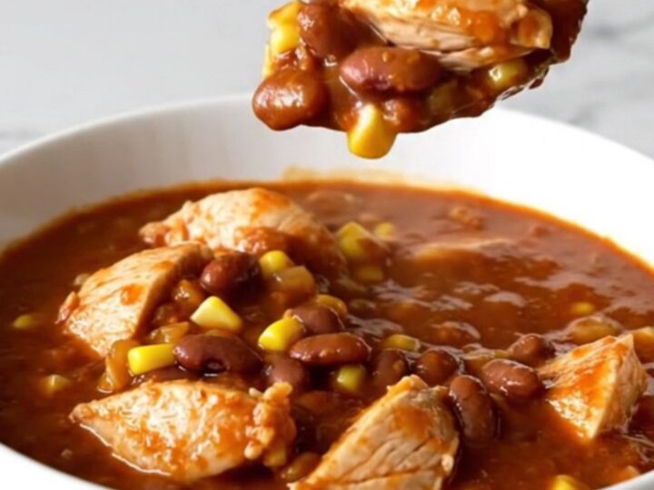 A shallow bowl filled with Crockpot Chicken Tamale Chili featuring chunks of white chicken, yellow corn