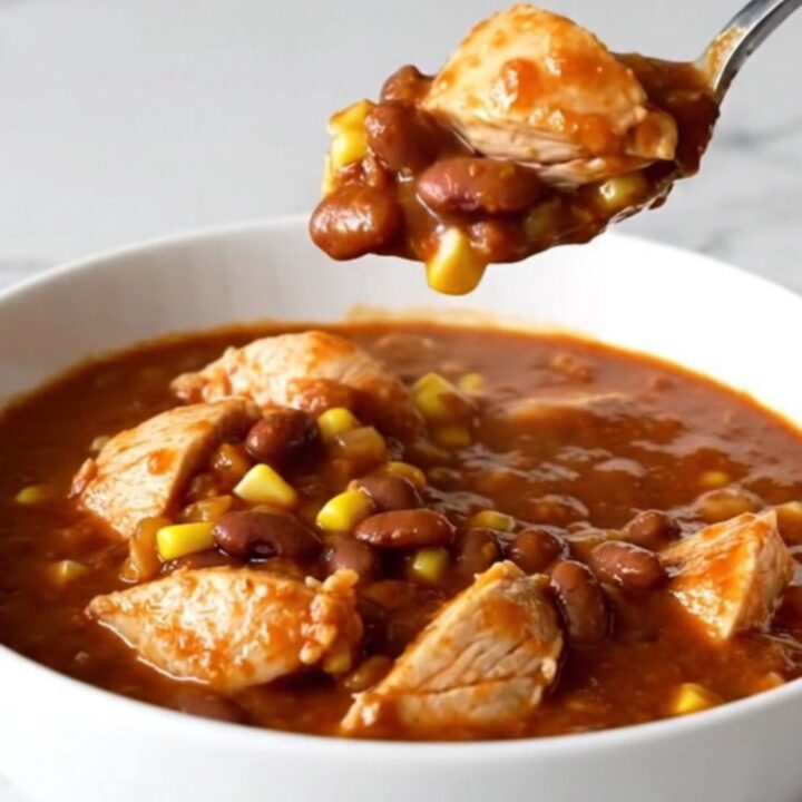 A shallow bowl filled with Crockpot Chicken Tamale Chili featuring chunks of white chicken, yellow corn