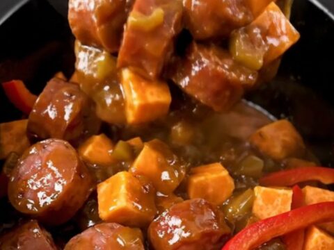 A close-up view of the finished jerk smoked sausage and sweet potato dish in a slow cooker.