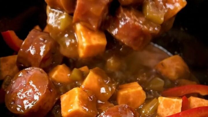 A close-up view of the finished jerk smoked sausage and sweet potato dish in a slow cooker.