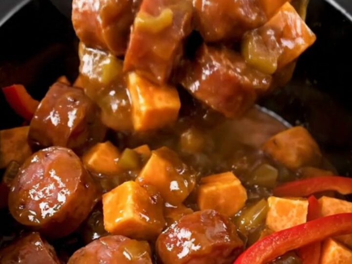 A close-up view of the finished jerk smoked sausage and sweet potato dish in a slow cooker.