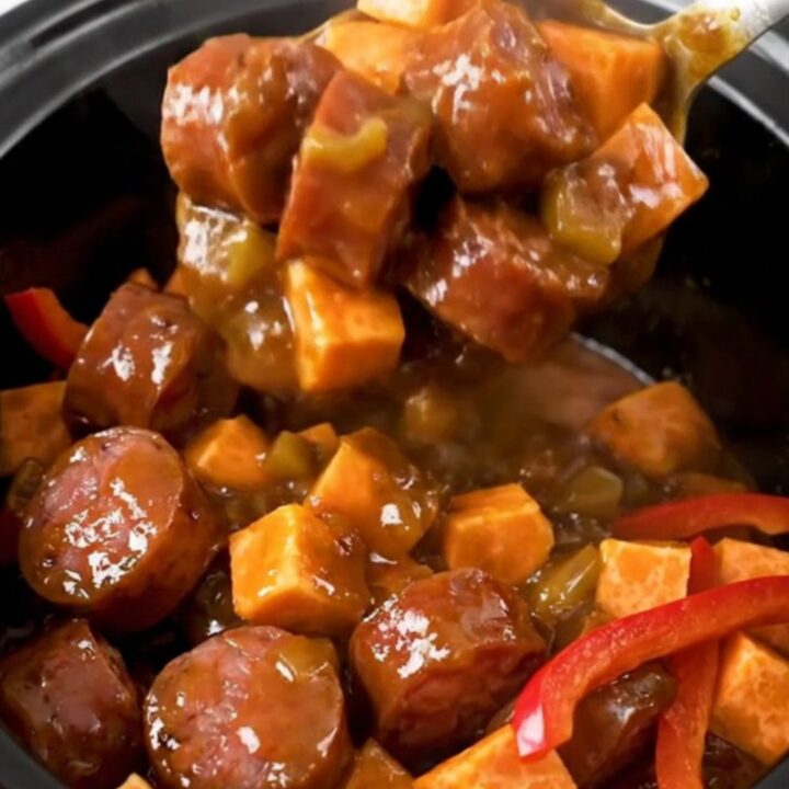 A close-up view of the finished jerk smoked sausage and sweet potato dish in a slow cooker.