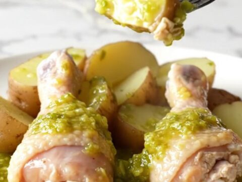 A close-up view of cooked chicken drumsticks and red potatoes served with salsa verde in a slow cooker.