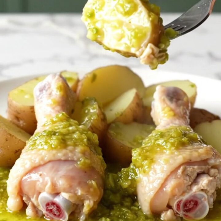 A close-up view of cooked chicken drumsticks and red potatoes served with salsa verde in a slow cooker.