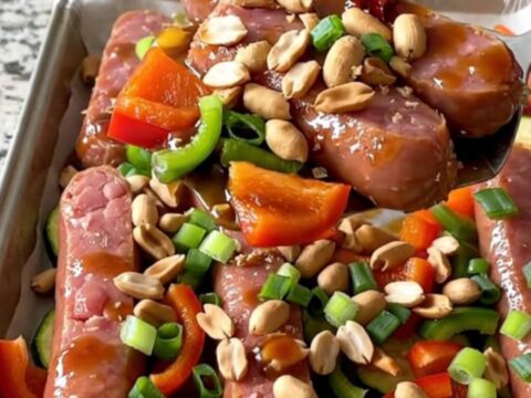 A sheet pan filled with golden-brown kielbasa coins, vibrant bell peppers, and zucchini tossed in a rich kung pao sauce.