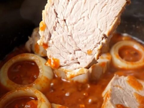 Close-up of tender honey chili crisp pork chops in a slow cooker, coated in a thick red sauce.