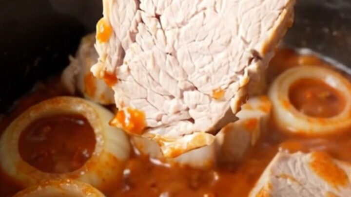 Close-up of tender honey chili crisp pork chops in a slow cooker, coated in a thick red sauce.