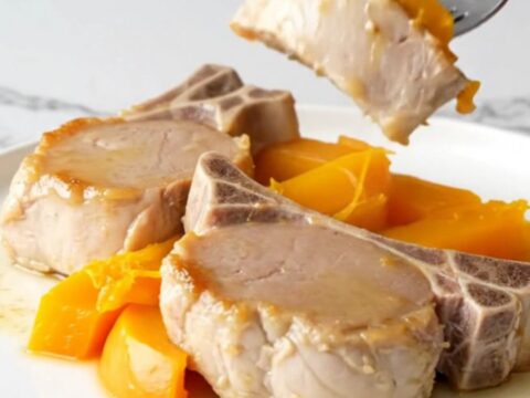A plate of tender cooked pork loin and soft acorn squash wedges with a light maple glaze.