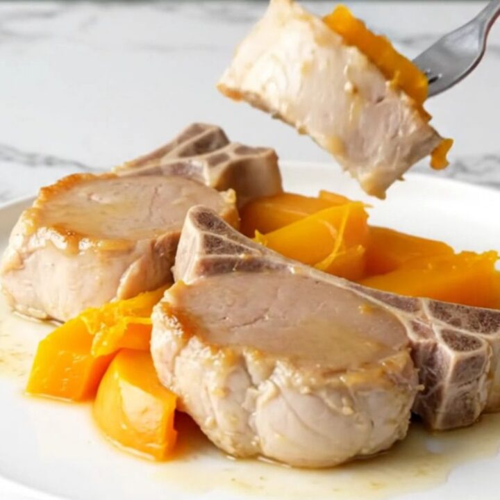 A plate of tender cooked pork loin and soft acorn squash wedges with a light maple glaze.