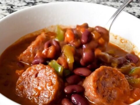 A hearty bowl of bratwurst chili with beans and peppers, steaming hot and ready to eat.