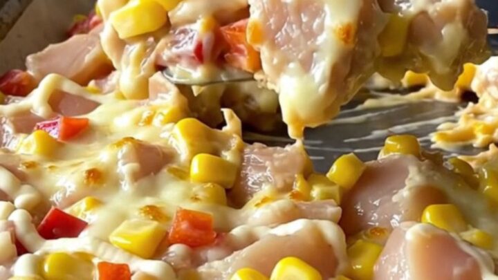 A sheet pan filled with golden, melted mozzarella cheese over cooked chicken chunks, corn, and red peppers.