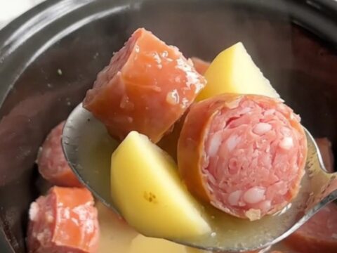 A close-up view of the slow cooker filled with golden potatoes and savory Italian sausage in a light lemony broth.