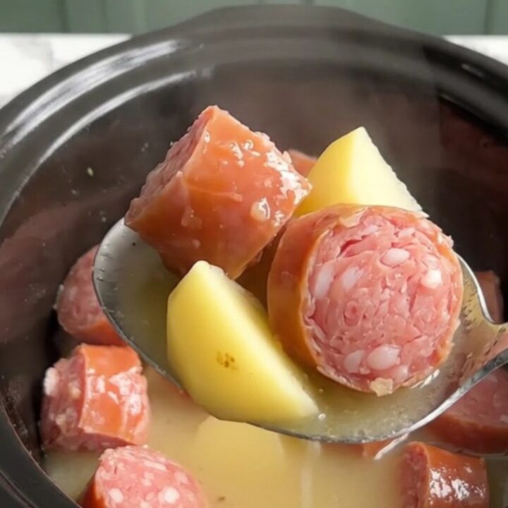 A close-up view of the slow cooker filled with golden potatoes and savory Italian sausage in a light lemony broth.