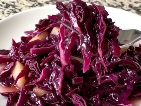 A vibrant heap of slow-cooked red cabbage and apples with a deep violet color and glossy sauce.