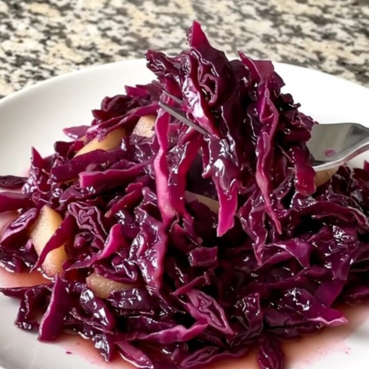 A vibrant heap of slow-cooked red cabbage and apples with a deep violet color and glossy sauce.