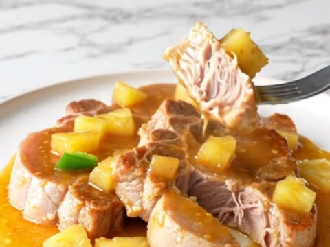 Bone-in pork shoulder steaks in a slow cooker with pineapple chunks and peppers.