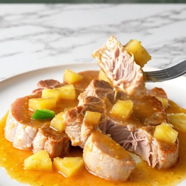 Bone-in pork shoulder steaks in a slow cooker with pineapple chunks and peppers.