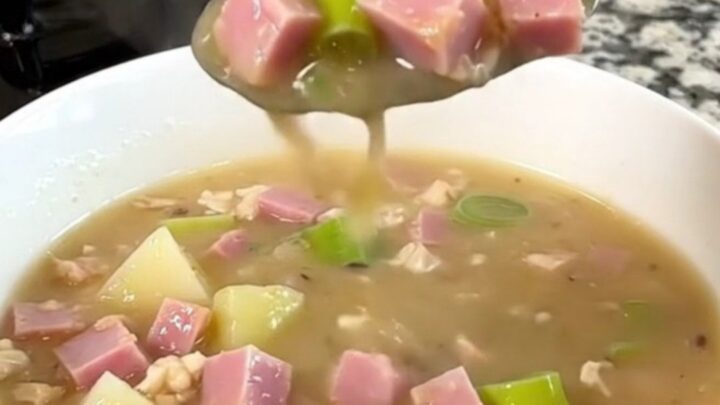 A close-up of the slow cooker filled with diced ham, leeks, and cubed potatoes in a golden broth.
