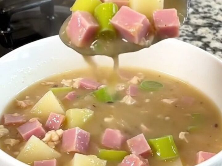 A close-up of the slow cooker filled with diced ham, leeks, and cubed potatoes in a golden broth.