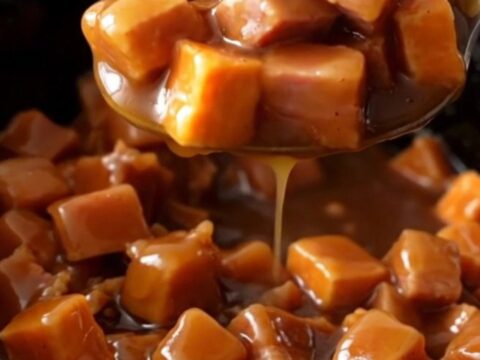 A close-up of tender ham chunks and bright orange sweet potatoes coated in a thick