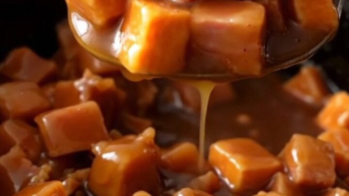 A close-up of tender ham chunks and bright orange sweet potatoes coated in a thick