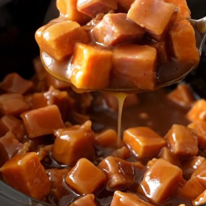 A close-up of tender ham chunks and bright orange sweet potatoes coated in a thick