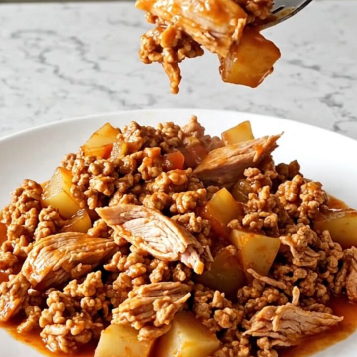 A hearty bowl of slow cooker ranchero ground turkey with potatoes and colorful bell peppers in a red sauce.