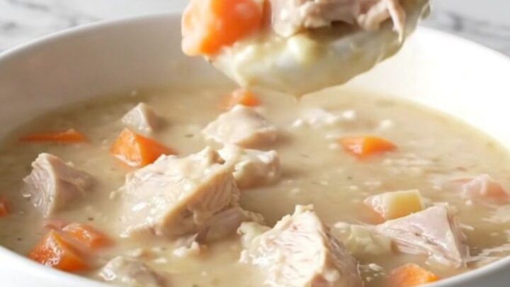 A bowl of creamy turkey and root vegetable chowder sitting on a marble counter.