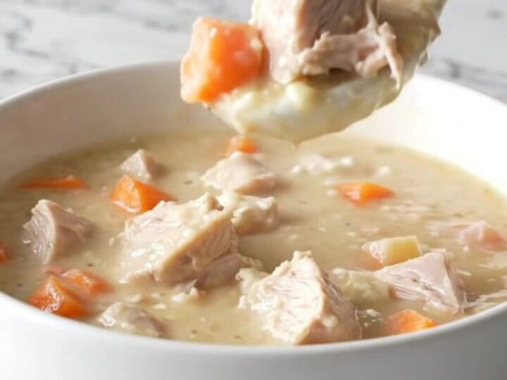 A bowl of creamy turkey and root vegetable chowder sitting on a marble counter.