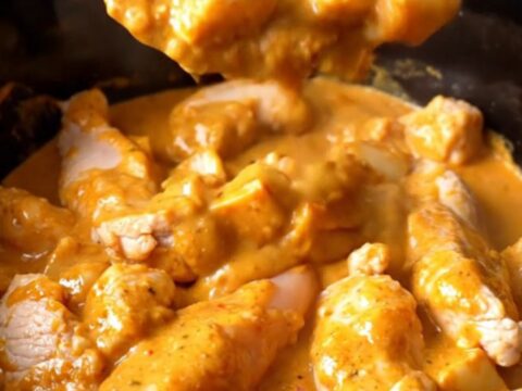 A close-up view of creamy buffalo chicken tenders and potatoes in a black slow cooker insert.