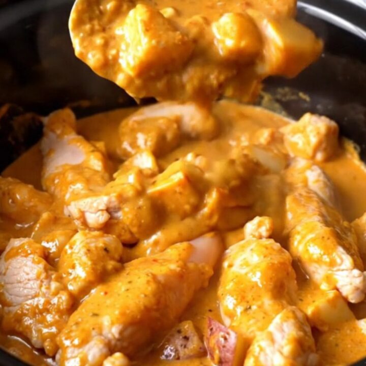 A close-up view of creamy buffalo chicken tenders and potatoes in a black slow cooker insert.