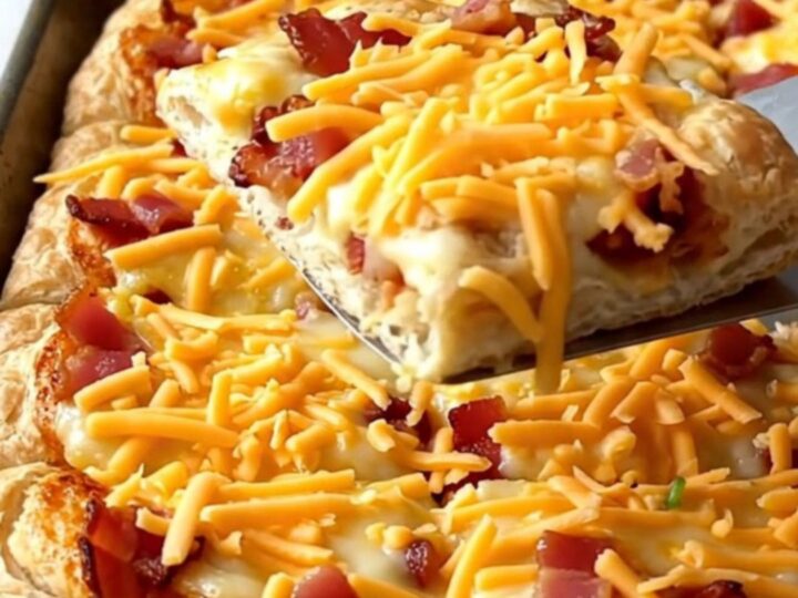 A sheet pan breakfast pizza with golden crust, eggs, bacon, and peppers.