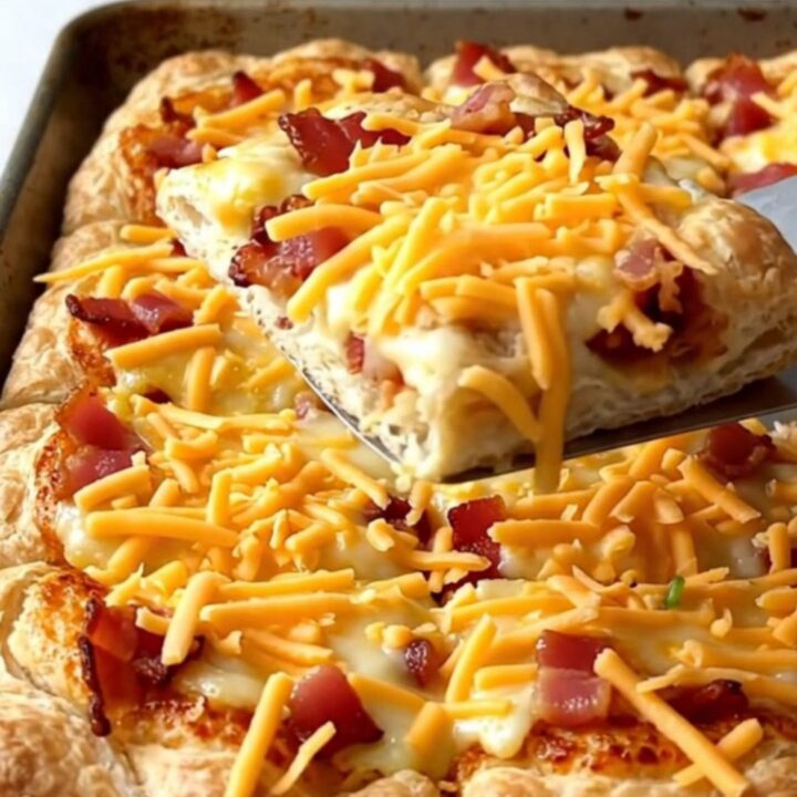A sheet pan breakfast pizza with golden crust, eggs, bacon, and peppers.