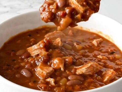 A warm bowl of mixed bean turkey chili with visible turkey crumbles and various beans in a rich tomato sauce.