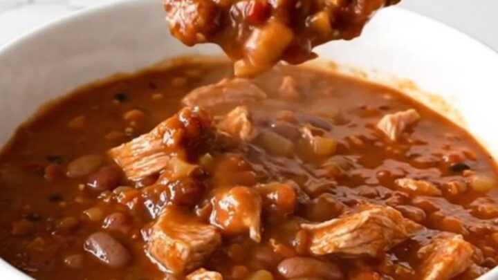 A warm bowl of mixed bean turkey chili with visible turkey crumbles and various beans in a rich tomato sauce.