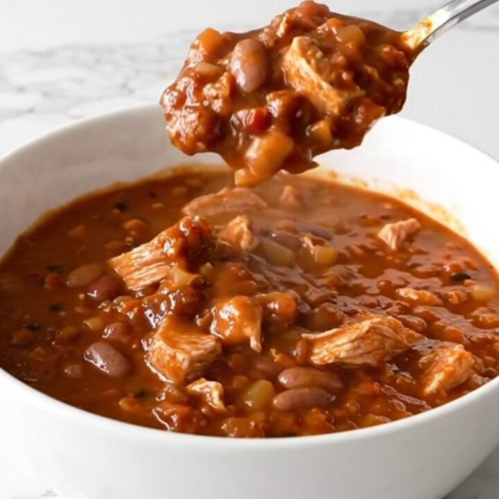 A warm bowl of mixed bean turkey chili with visible turkey crumbles and various beans in a rich tomato sauce.