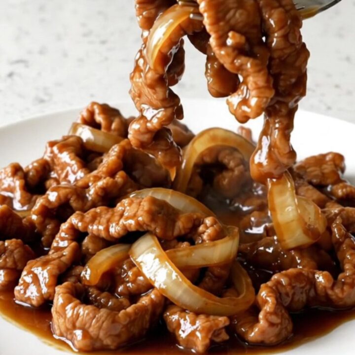 A bowl of tender Crockpot Pork Bulgogi served over white rice with sesame seeds and onions.