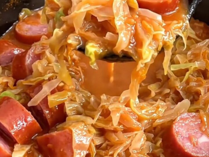 A bowl of Polish Hunter's Stew featuring chunks of kielbasa, cabbage, and sauerkraut in a rich red tomato sauce.