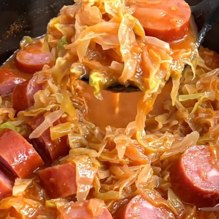A bowl of Polish Hunter's Stew featuring chunks of kielbasa, cabbage, and sauerkraut in a rich red tomato sauce.